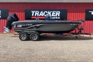 The Image of 2021 Nitro ZV19 boat on trailer, parked in front of Tracker Boats signage. - 1