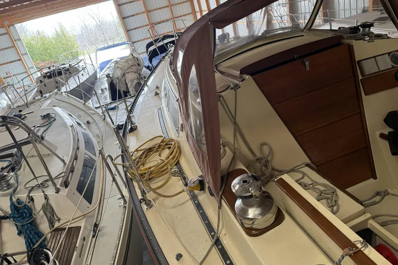 Slide: The Image of 1977 Islander 32 sailboat in storage, surrounded by other boats in a covered facility. - 10