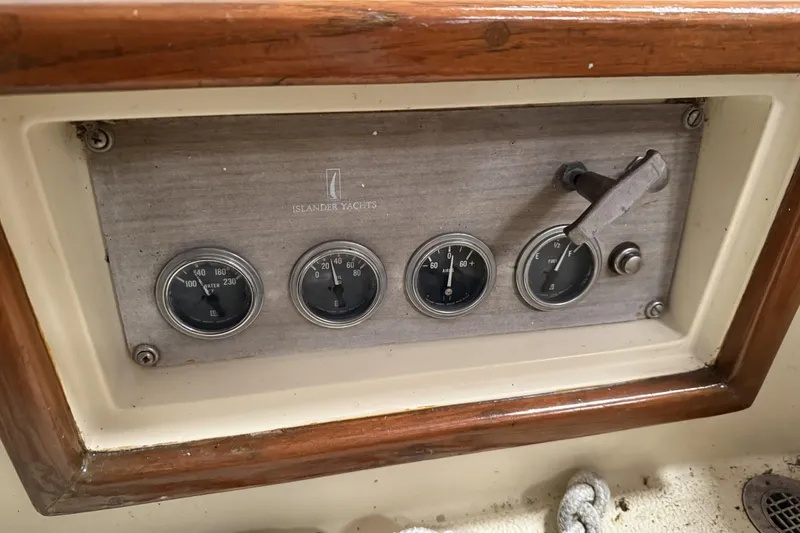 Slide: The Image of 1977 Islander 32 yacht dashboard with gauges and controls, featuring wood trim. - 14