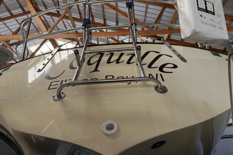 Slide: The Image of 1977 Islander 32 sailboat stern with ladder, docked indoors, displaying name "Coquille." - 3
