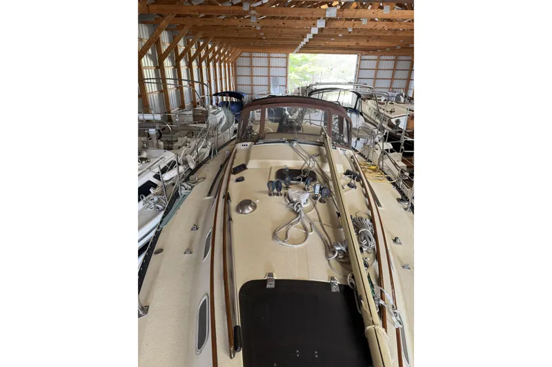 Slide: The Image of 1977 Islander 32 sailboat in a wooden boathouse, surrounded by other vessels. - 5