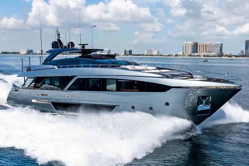 The Image of Luxurious 2020 Riva 110' Dolcevita yacht cruising on open water, city skyline in background. - 1