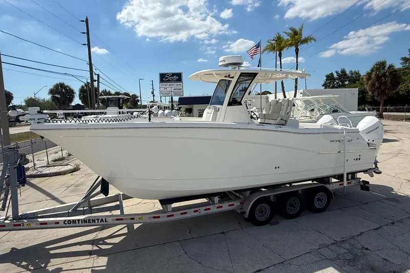 Slide: The Image of 2024 World Cat 280 CC-X boat on trailer, parked outdoors under a clear sky. - 4