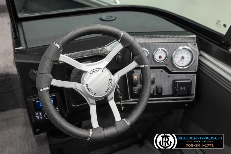 Slide: The Image of Steering wheel and dashboard of 2026 Lund 1975 Tyee boat, featuring modern controls. - 32