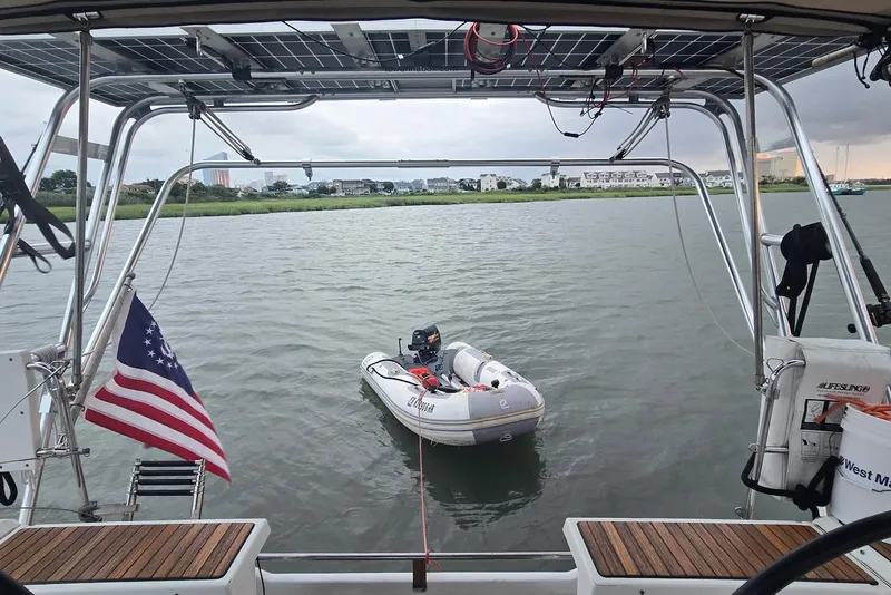 Slide: The Image of Beneteau Oceanis 38.1 sailboat with dinghy, solar panels, and American flag on calm water. - 14