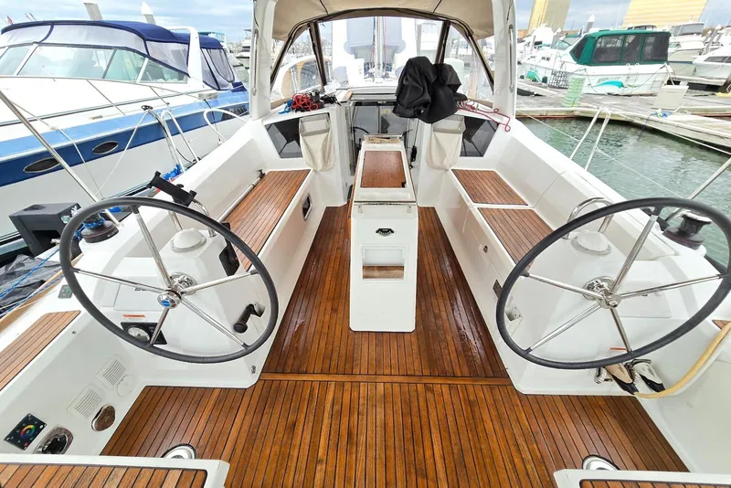 Slide: The Image of 2018 Beneteau Oceanis 38.1 yacht cockpit with dual steering wheels and wooden deck. - 15