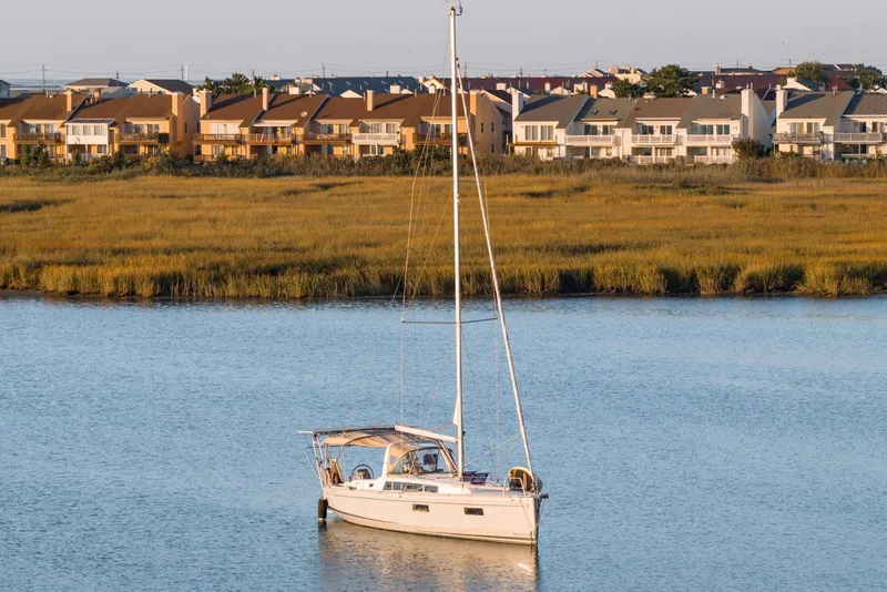 Slide: The Image of Sailboat Beneteau Oceanis 38.1, 2018 model, anchored near waterfront homes. - 2