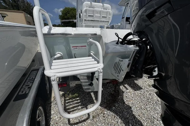 Slide: The Image of 2026 Blazer Bay 2440 boat with ladder and motor, parked on gravel. - 4