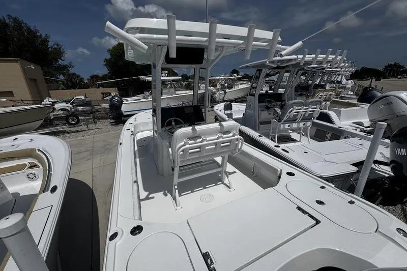 Slide: The Image of 2026 Blazer Bay 2440 boat with center console and seating, docked under a cloudy sky. - 5