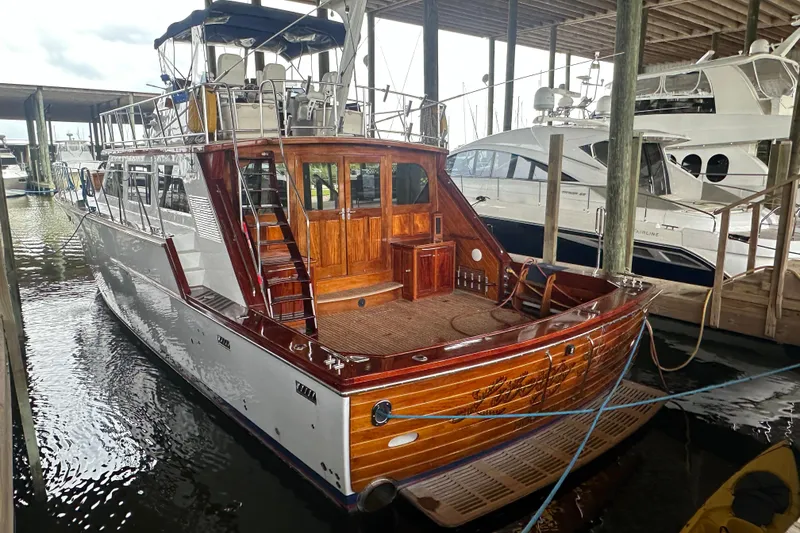 The Image of 1980 Bertram 58 Convertible yacht docked, showcasing elegant wooden detailing and spacious deck. - 0