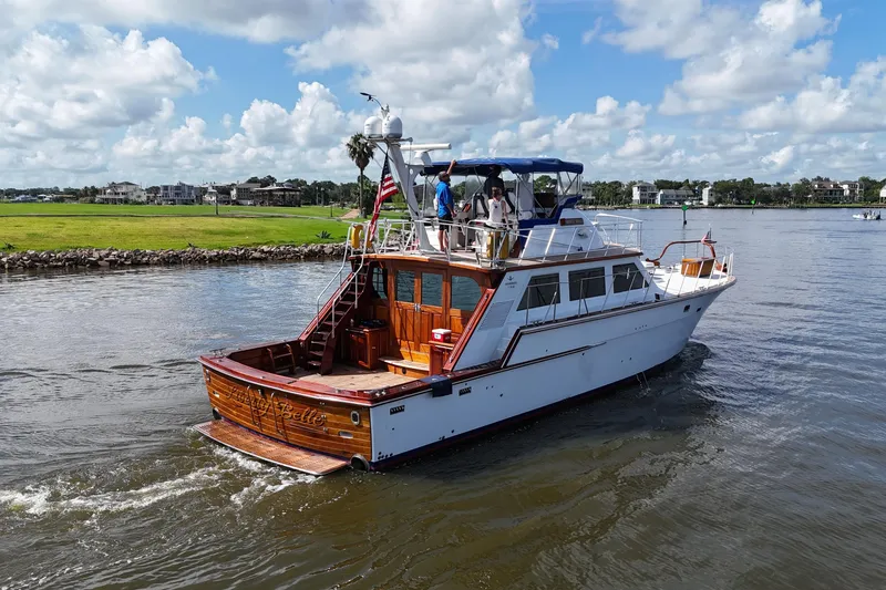 Slide: The Image of 1980 Bertram 58 Convertible yacht cruising on a sunny day, with scenic waterfront views. - 10