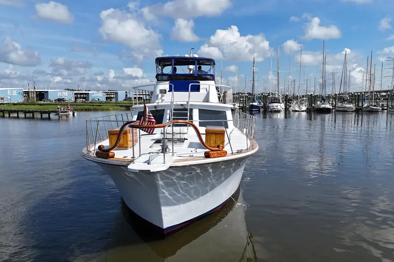 Slide: The Image of 1980 Bertram 58 Convertible yacht docked in a marina under a blue sky. - 11