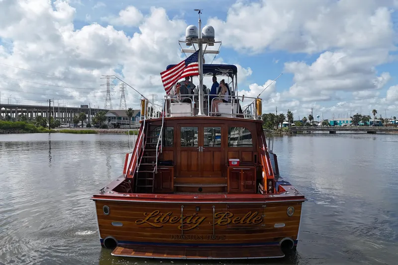Slide: The Image of 1980 Bertram 58 Convertible yacht "Liberty Belle" on water, American flag flying. - 12