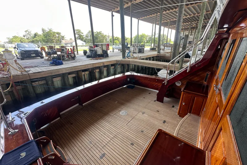 Slide: The Image of Bertram 58 Convertible 1980 yacht docked, showcasing spacious wooden deck and elegant design. - 14