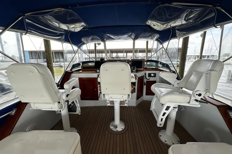 Slide: The Image of Interior view of a 1980 Bertram 58 Convertible yacht cockpit with white seating and wooden accents. - 19