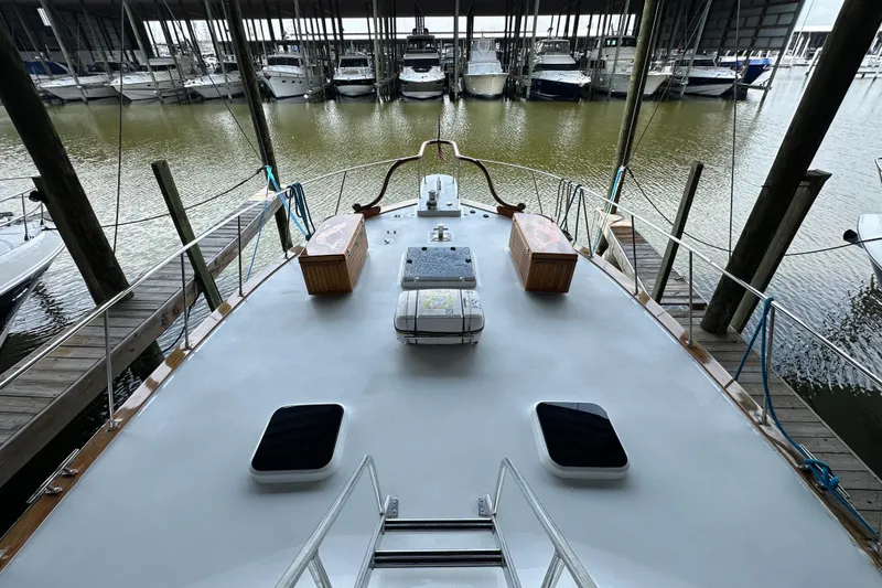 Slide: The Image of 1980 Bertram 58 Convertible yacht docked in a marina, showcasing spacious deck and moored boats. - 29
