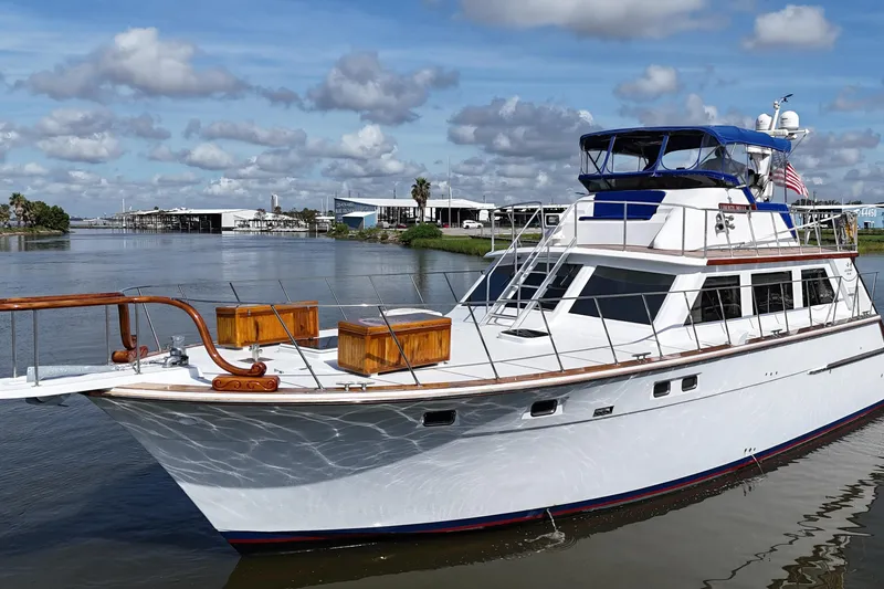 Slide: The Image of 1980 Bertram 58 Convertible yacht on calm water under a partly cloudy sky. - 3