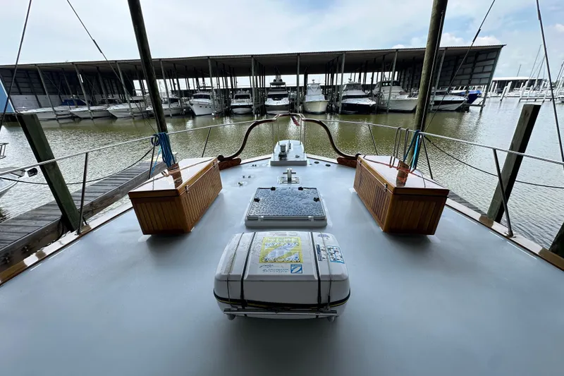 Slide: The Image of 1980 Bertram 58 Convertible yacht docked at marina with covered slips in background. - 30