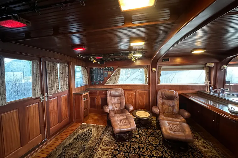 Slide: The Image of Luxurious interior of a 1980 Bertram 58 Convertible yacht with leather chairs and wood paneling. - 38