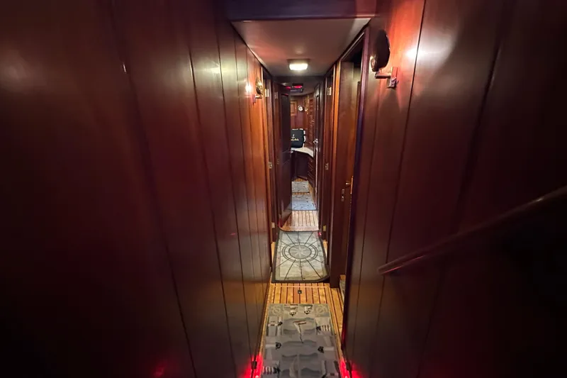 Slide: The Image of Narrow wooden hallway inside a 1980 Bertram 58 Convertible yacht, featuring warm lighting. - 57
