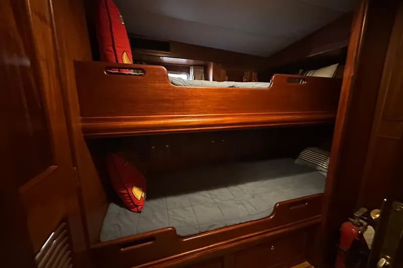 Slide: The Image of Bunk beds in 1980 Bertram 58 Convertible yacht cabin, featuring wooden finish and cozy bedding. - 59