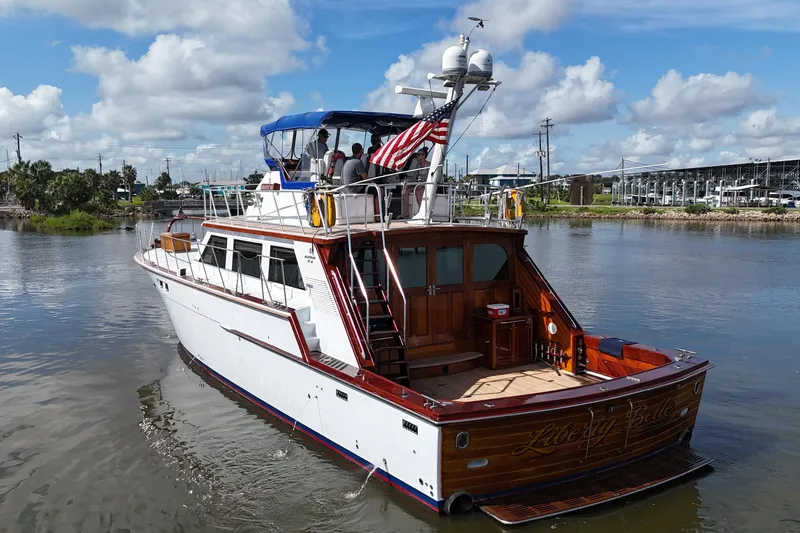Slide: The Image of 1980 Bertram 58 Convertible yacht cruising on a sunny day, featuring an American flag. - 6