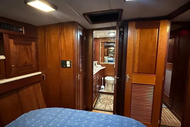 Slide: The Image of Interior of a 1980 Bertram 58 Convertible yacht, featuring wood paneling and a compact bathroom. - 67