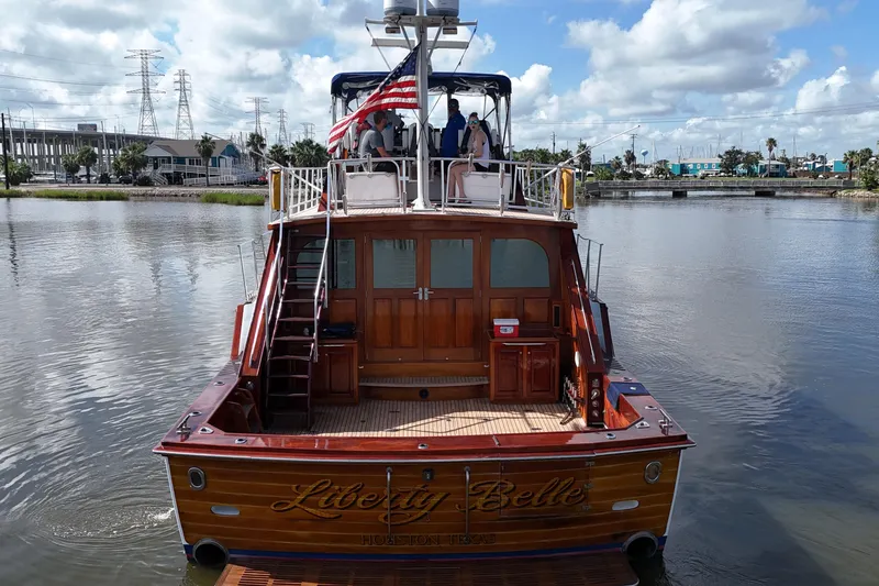Slide: The Image of 1980 Bertram 58 Convertible yacht "Liberty Belle" on calm waters, showcasing elegant wooden design. - 7