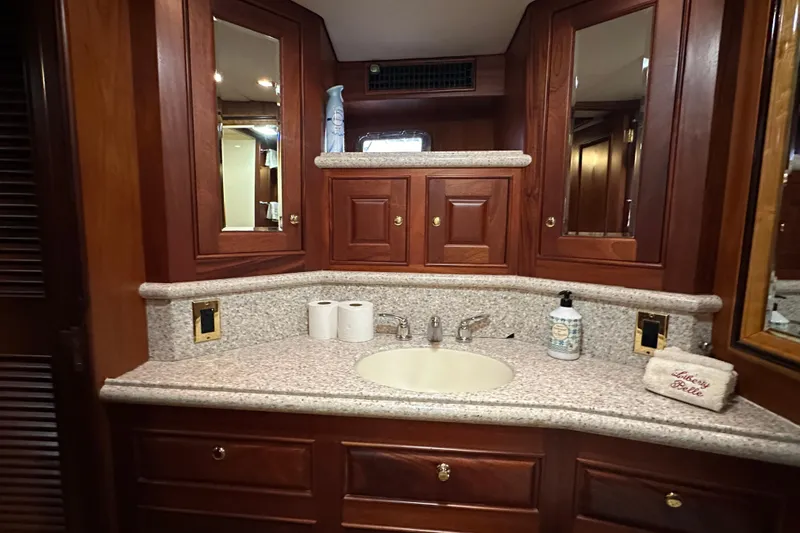 Slide: The Image of Luxurious bathroom vanity in a 1980 Bertram 58 Convertible yacht, featuring wood cabinetry and granite countertop. - 74