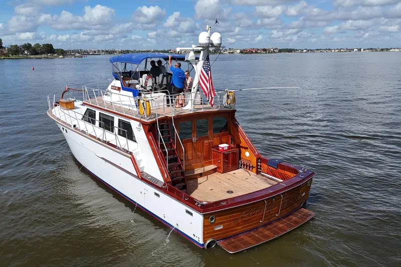 Slide: The Image of 1980 Bertram 58 Convertible yacht cruising on a calm lake under a partly cloudy sky. - 8