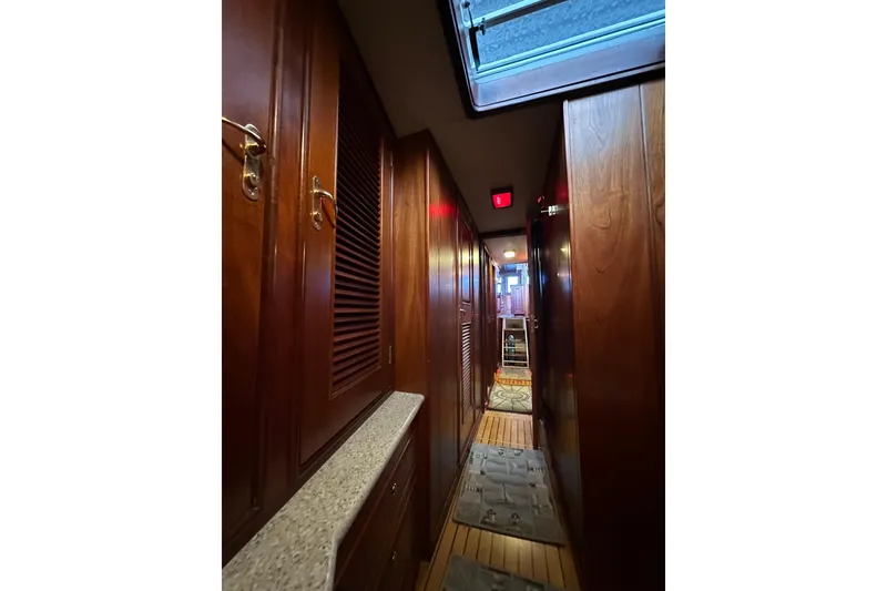 Slide: The Image of Narrow hallway inside 1980 Bertram 58 Convertible yacht with wooden cabinetry and carpeted floor. - 81