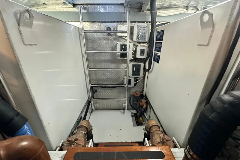 Slide: The Image of Engine room of a 1980 Bertram 58 Convertible yacht, featuring control panels and piping. - 84