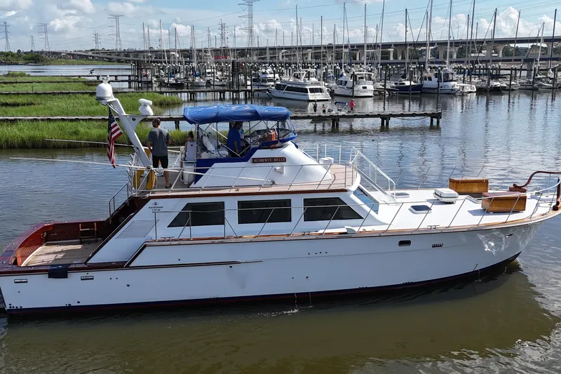 Slide: The Image of 1980 Bertram 58 Convertible yacht docked in a marina with other boats. - 9