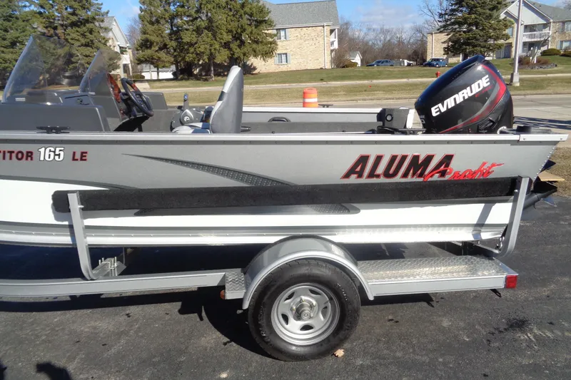 Slide: The Image of 2015 Alumacraft Competitor 165 CS boat on trailer with Evinrude motor, parked outdoors. - 20