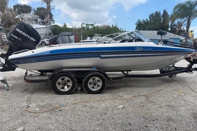 The Image of 2008 Champion 214 SX boat with Mercury engine on trailer, parked outdoors. - 0