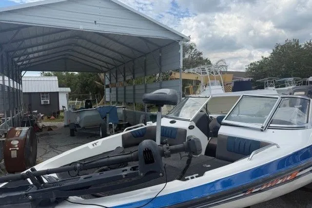 Slide: The Image of 2008 Champion 214 SX boat in storage, featuring blue accents and a covered shelter. - 2