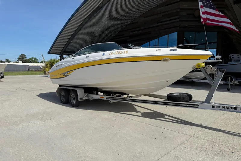 Slide: The Image of 2002 Chaparral 220 SSi boat on trailer, parked outdoors near a modern building. - 2