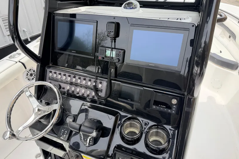 Slide: The Image of 2024 Tidewater 256 LXF boat dashboard with dual screens, steering wheel, and control panel. - 11