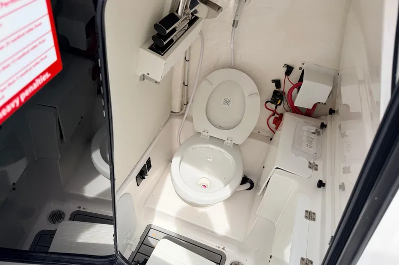 Slide: The Image of 2024 Tidewater 256 LXF boat interior with a compact marine toilet and storage compartments. - 27