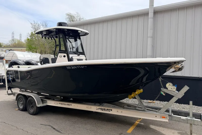 Slide: The Image of 2024 Tidewater 256 LXF boat on trailer, parked outdoors near a building. - 3