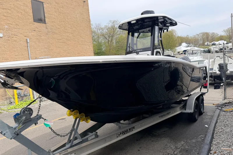 Slide: The Image of 2024 Tidewater 256 LXF boat on trailer, black hull, parked outdoors. - 4