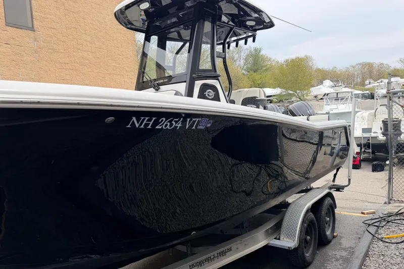 Slide: The Image of 2024 Tidewater 256 LXF boat on trailer, black hull, parked outdoors. - 6