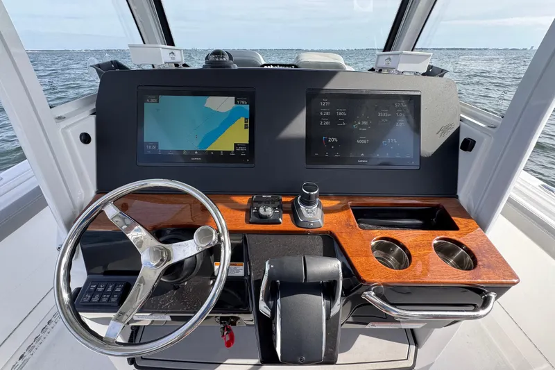 Slide: The Image of 2025 Everglades 315 Center Console helm with dual displays and wooden accents on open water. - 25