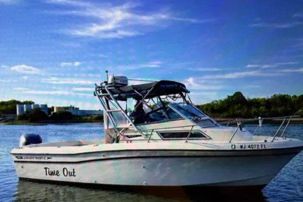 Slide: The Image of 1994 Grady-White Explorer 244 boat named "Time Out" on calm water under blue sky. - 17