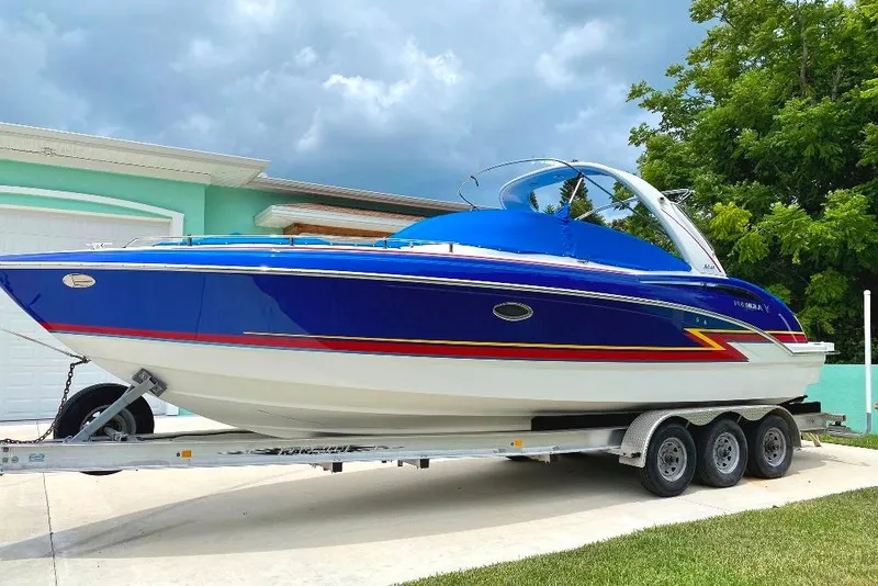 The Image of 2019 Formula 310 Bowrider boat on trailer, vibrant blue and white design, parked outdoors. - 0