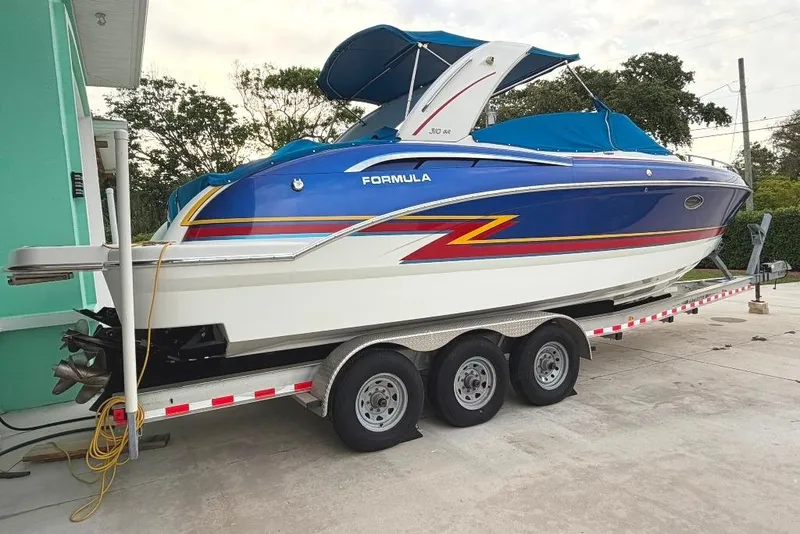 Slide: The Image of 2019 Formula 310 Bowrider boat on trailer, blue and white design, parked outdoors. - 7