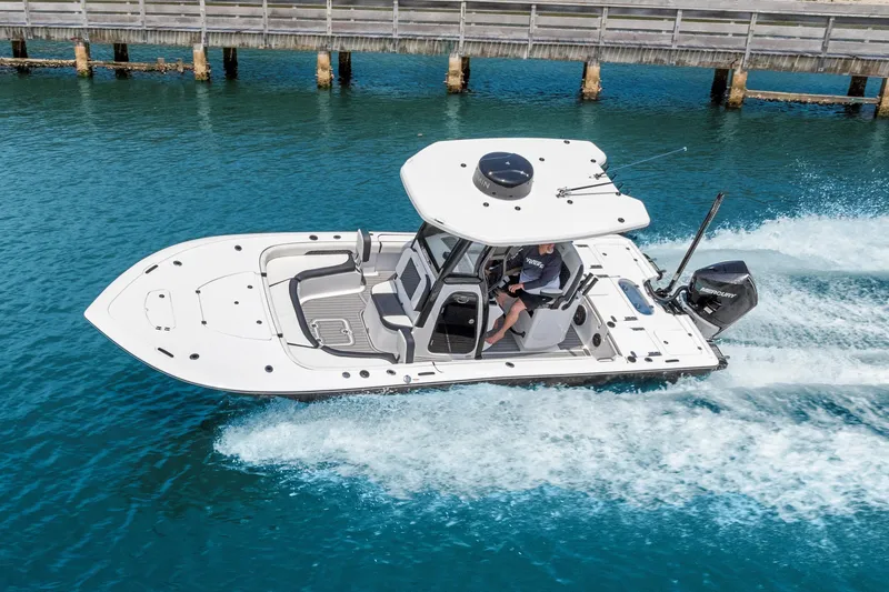 Slide: The Image of 2026 Tidewater 2500 Carolina Bay boat cruising on clear blue water near a wooden pier. - 6