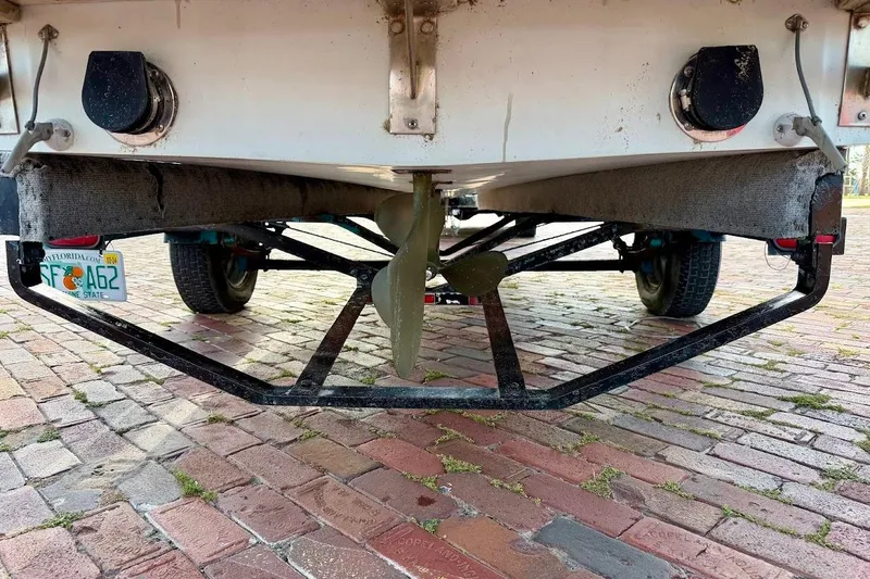 Slide: The Image of 1981 SKI NAUTIQUE boat on trailer, showing propeller and license plate, parked on brick pavement. - 12