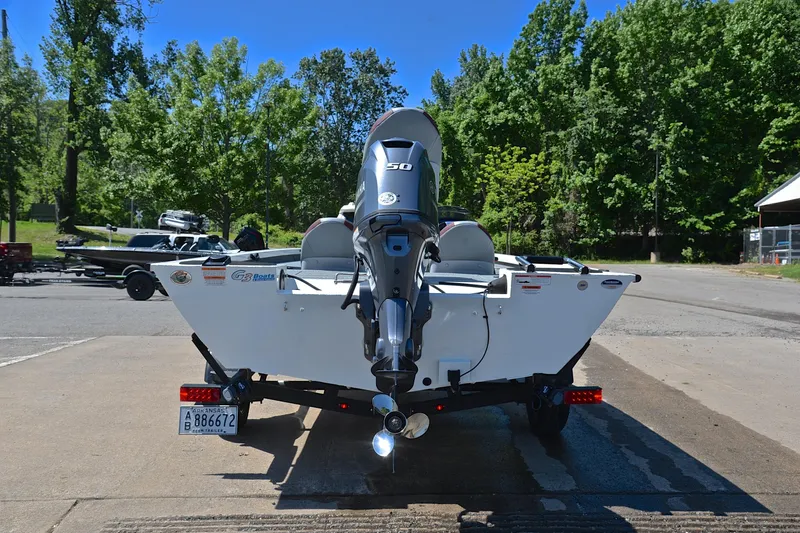 Slide: The Image of 2023 G3 Sportsman 1610 boat with outboard motor on trailer, parked near trees. - 13