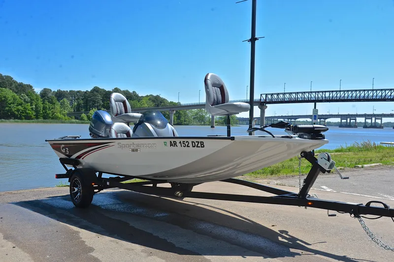 Slide: The Image of 2023 G3 Sportsman 1610 boat on trailer by a river, under a clear blue sky. - 16